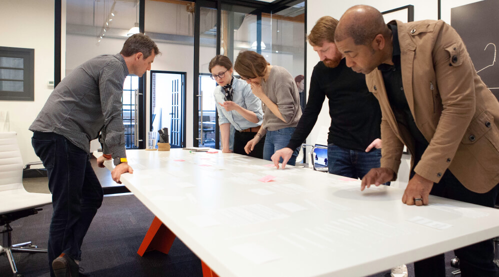 People gathered around a large table sorting ideas on paper
