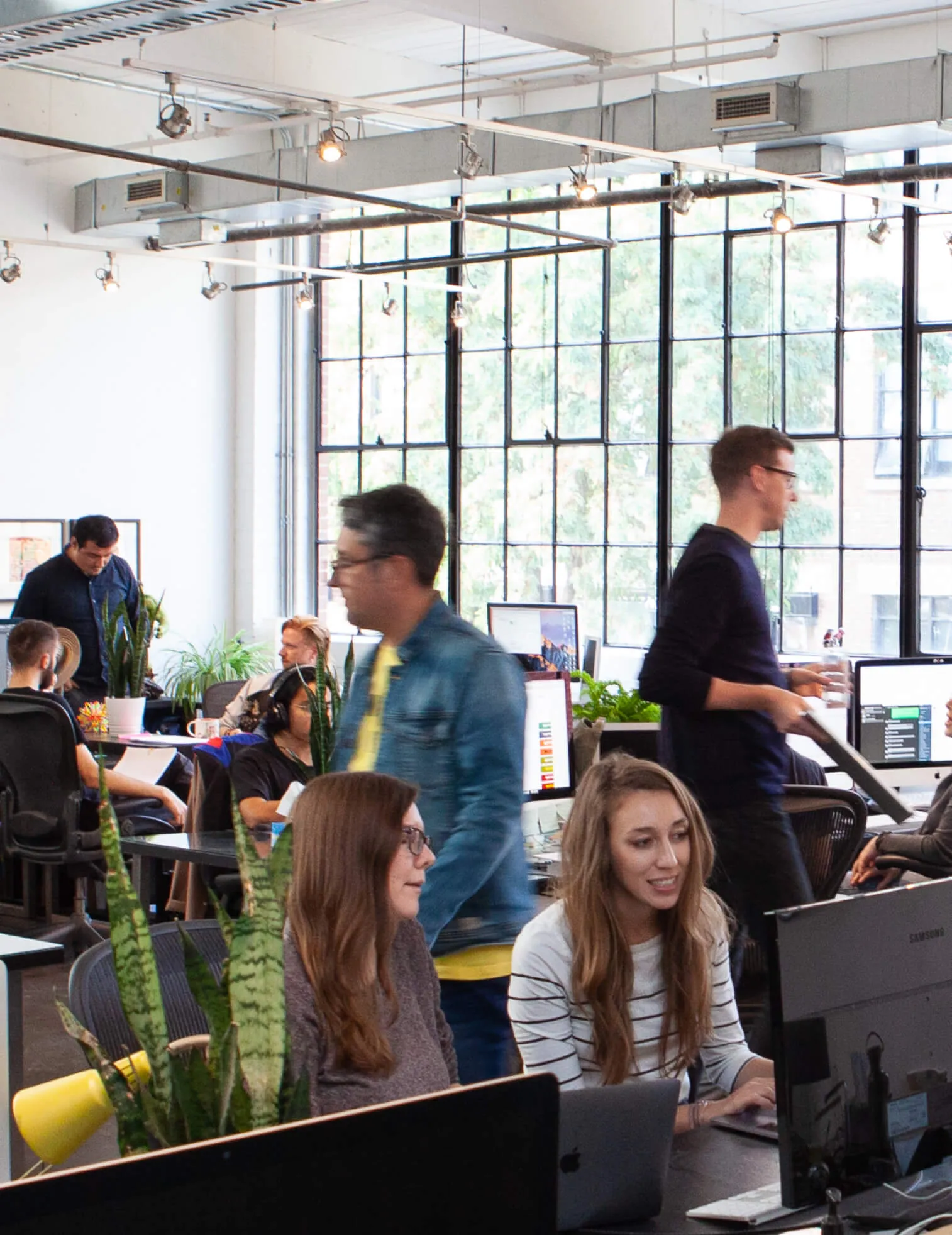 A diverse team of people working in a modern office with large windows.